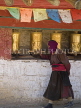 CHINA, Sichuan Province, Daocheng, Tibetan pilgrim spins prayer wheels walking around a stupa, CH1502JPL