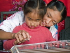 CHINA, Yunnan Province, Lijiang, girl learning to play traditional instrument, CH1570JPL
