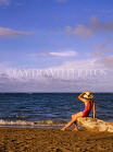 DOMINICAN REPUBLIC, North Coast, Playa Dorada, tourist on beach, seated on tree trunk, DR273JPL