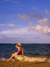 DOMINICAN REPUBLIC, North Coast, Playa Dorada, tourist on beach, seated on tree trunk, DR332JPL