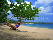 DOMINICAN REPUBLIC, North Coast, Playa Dorada, tourist relaxing on tree trunk, DR274JPL