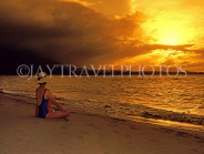 DOMINICAN REPUBLIC, North Coast, Playa Dorada, tourist seated on beach, watching sunset, DR279JPL