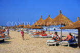 GAMBIA, Kotu Beach, sunbathers and thatched sunshades, GAM916JPL