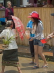 LAOS, Luang Prabang, Songkran Water Festival, old woman defends herself from a soaking, LAO95JPL