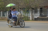 LAOS, Luang Prabang, street scene, moped rider, and passenger with umbrella, LAO129JPL