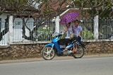 LAOS, Luang Prabang, street scene, moped rider, and passenger with umbrella, LAO130JPL