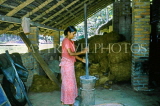SRI LANKA, rural scene, woman pounding rice (into flour), in large motar and pestle, SLK1850JPL