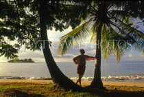 ST LUCIA, Choc Beach and tourist standing by coconut tree, STL729JPL