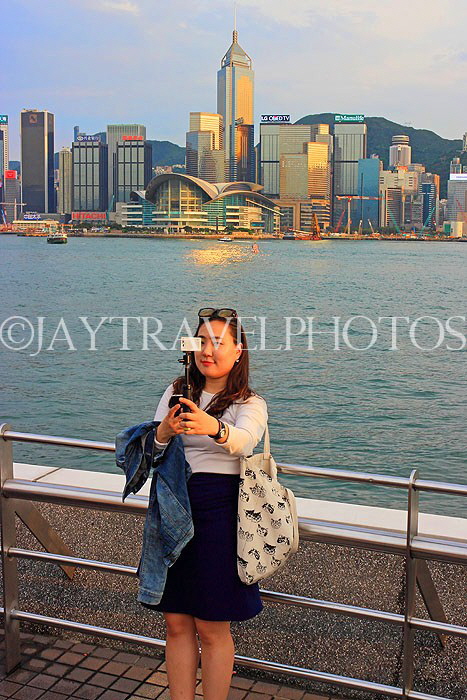 HONG KONG, Kowloon, Tsim Sha Tsui Promenade, gilr taking selfie against HK skyline, HK1264JPL